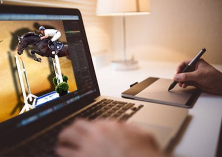 Eine Person arbeitet an einem Laptop mit einem Bild eines springenden Pferdes.